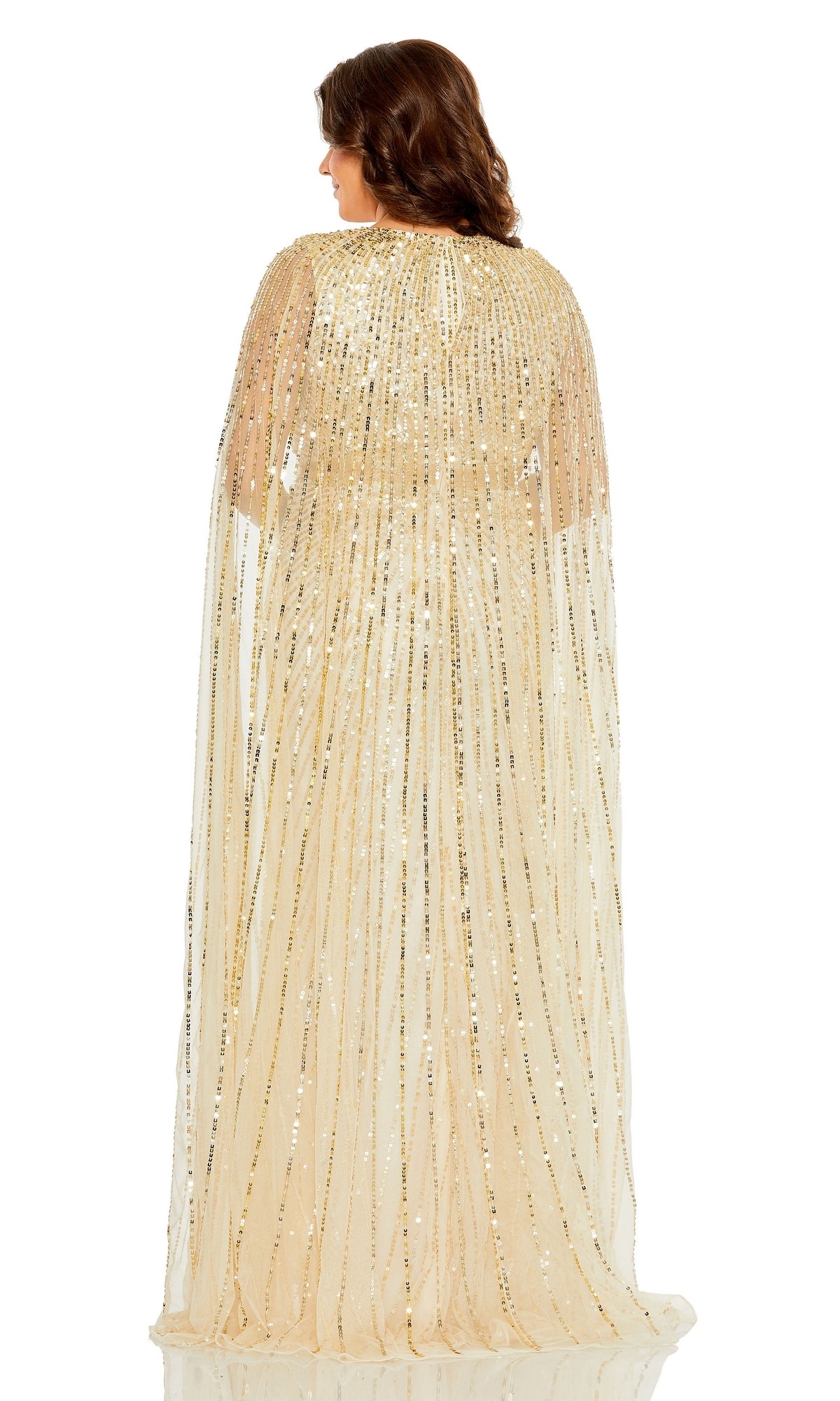 A woman faces away from the camera in the Mac Duggal Long Plus-Size Formal Dress 5804, a floor-length gold sequin gown with a sheer cape—an elegant choice for special occasions.